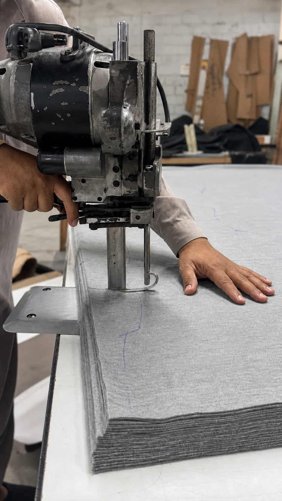 Fabric cutting machine shaping layered fabric panels on a production table