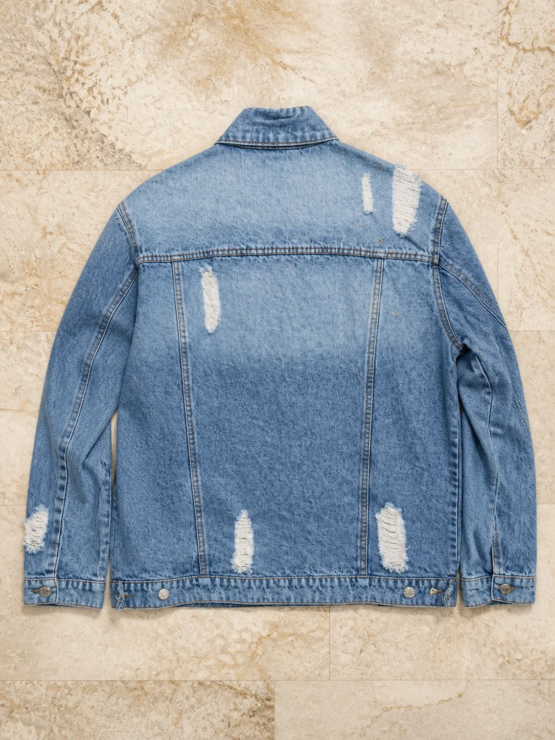 Back of a distressed denim jacket on marble
