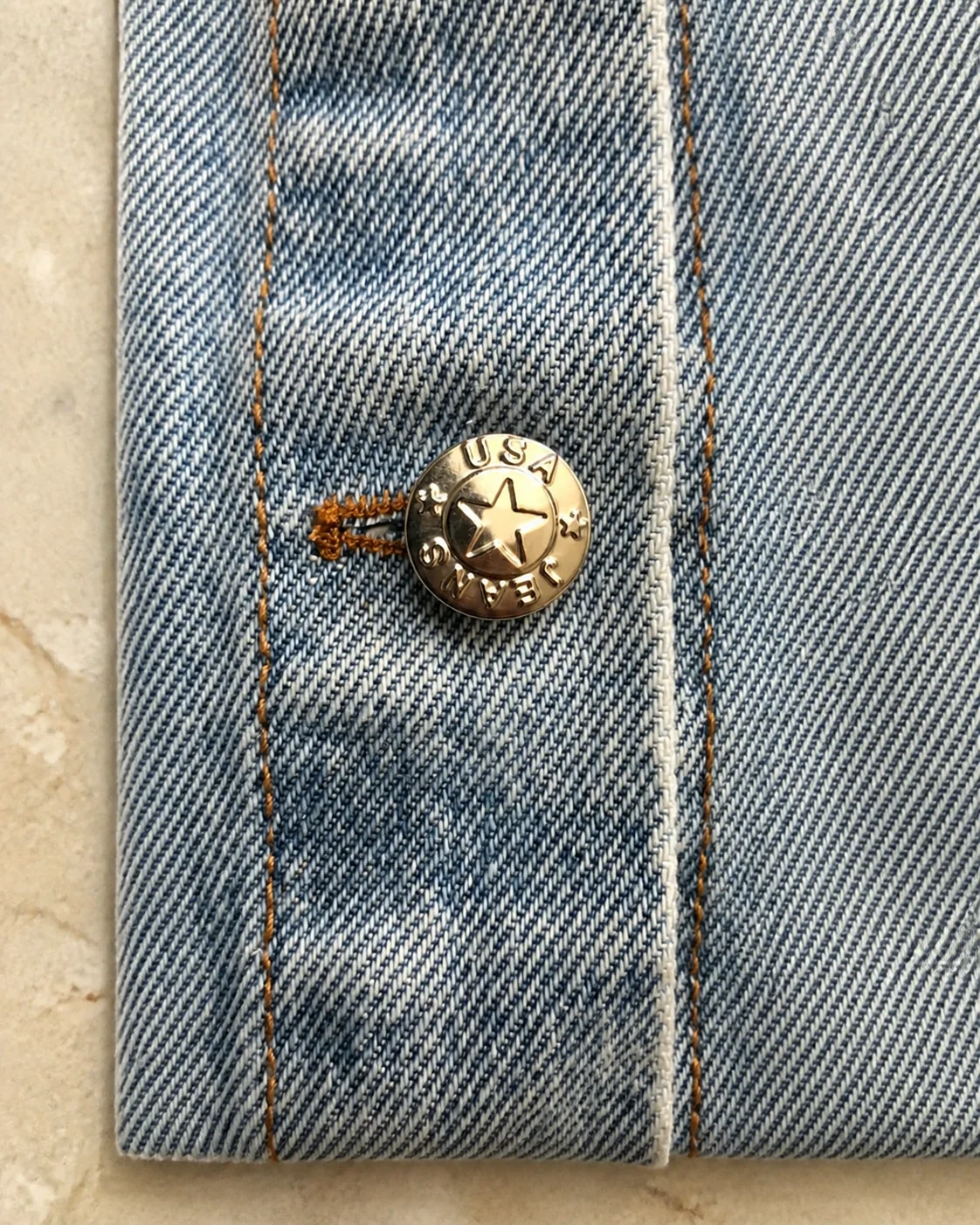 Close-up of denim jacket button and fabric detail