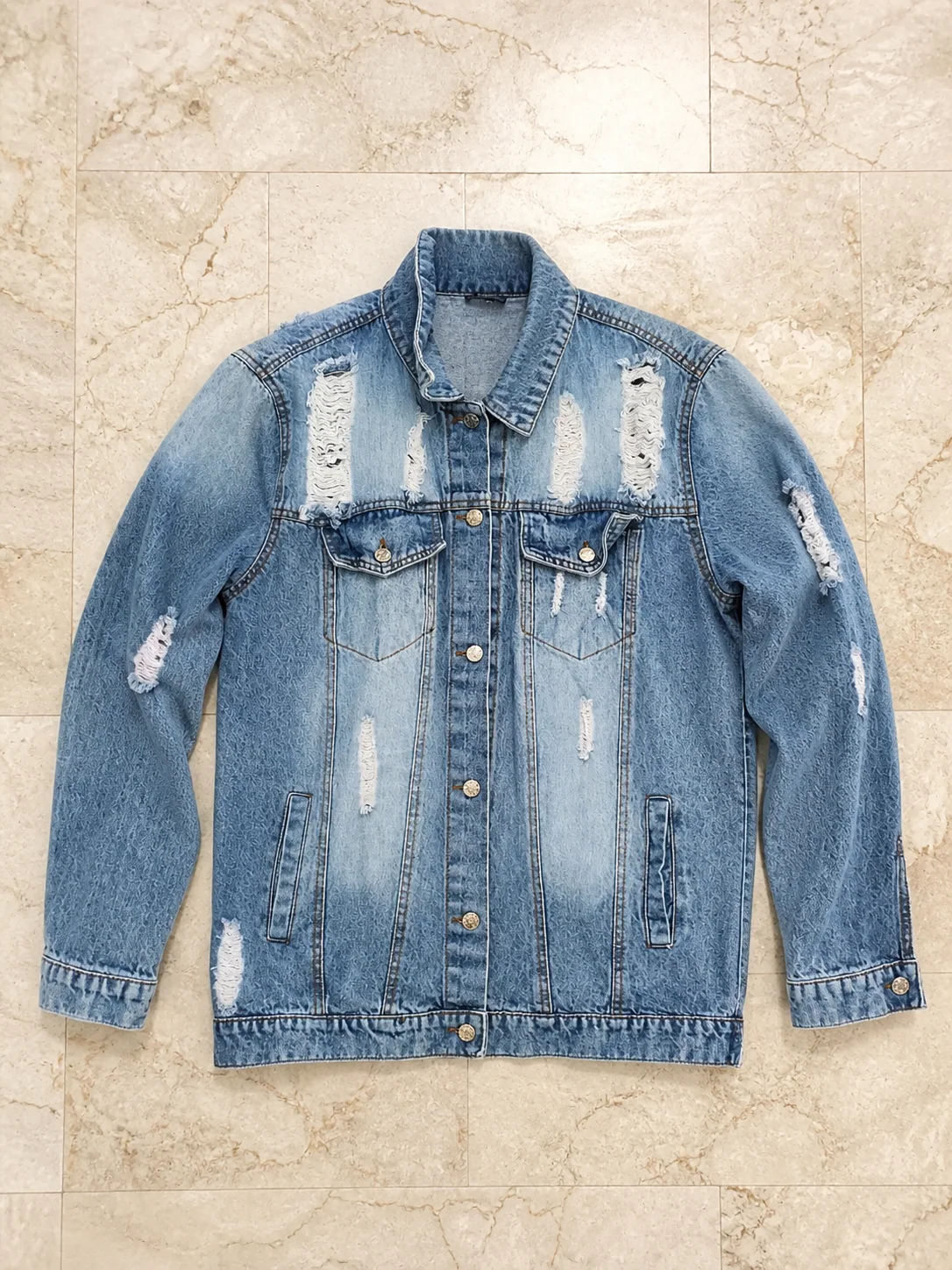 Front of a distressed denim jacket on marble