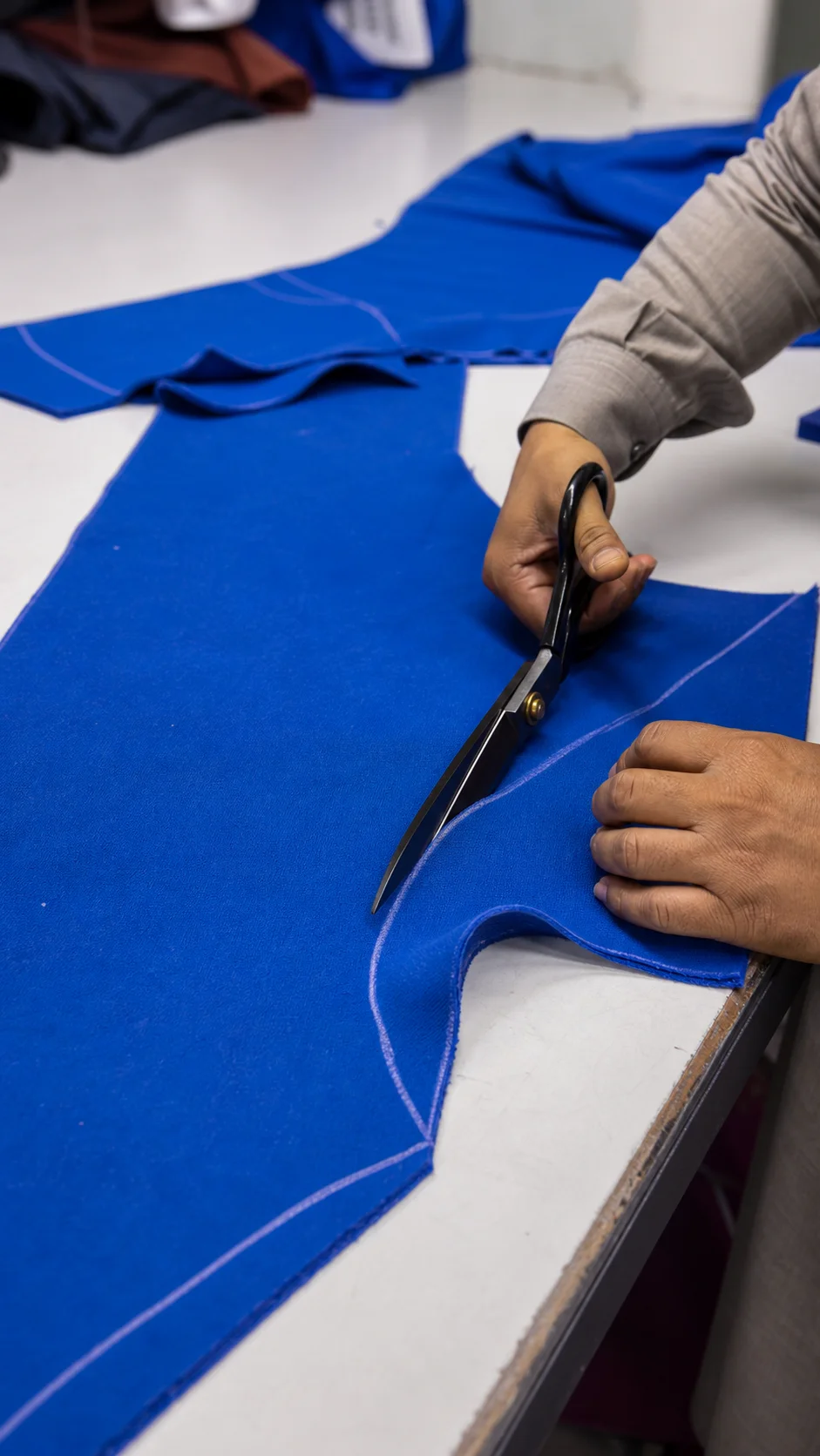 Blue fabric cut by hand along chalk garment pattern lines