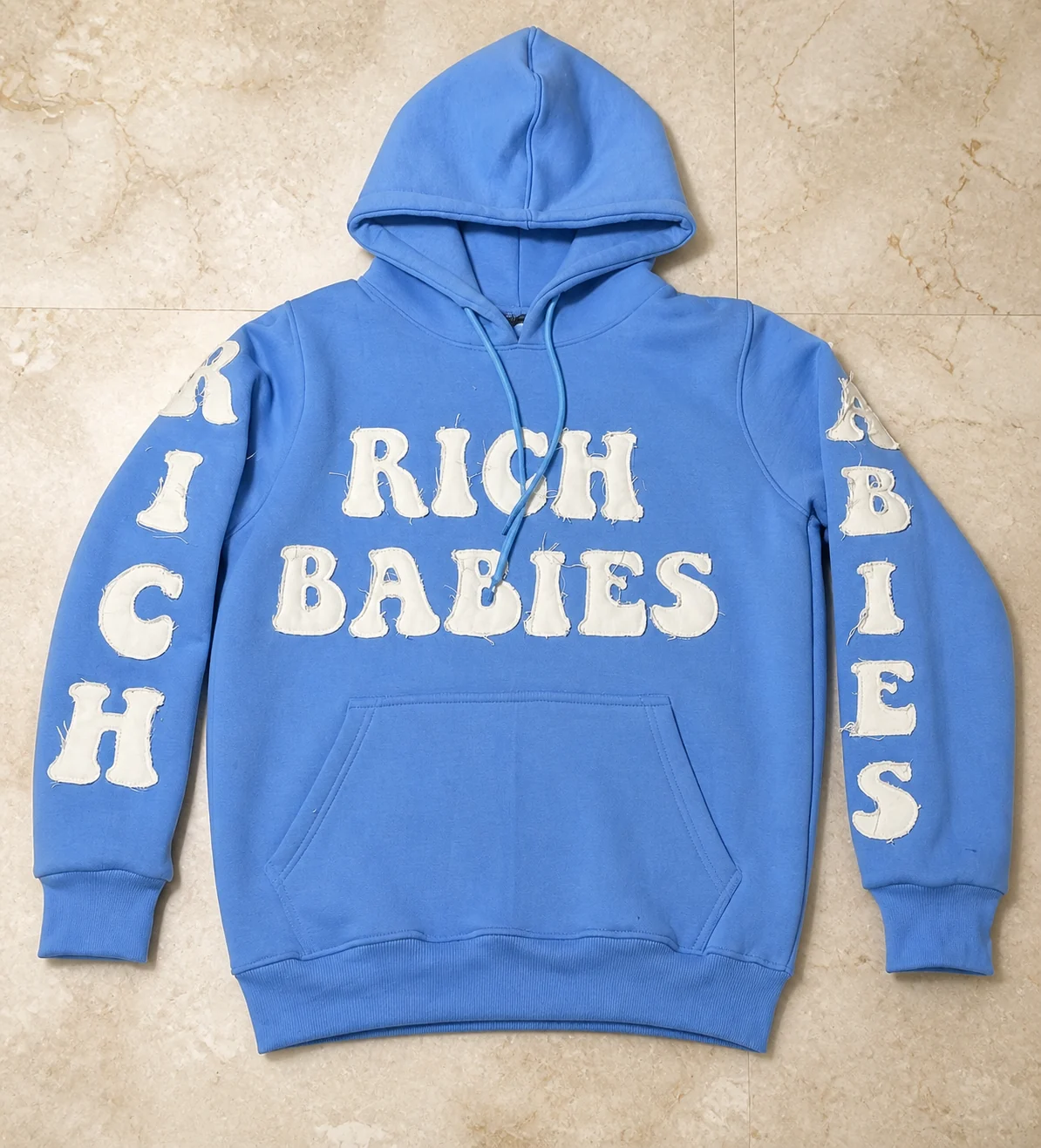 Blue pullover hoodie with raw-edge white appliqué lettering on the chest and sleeves