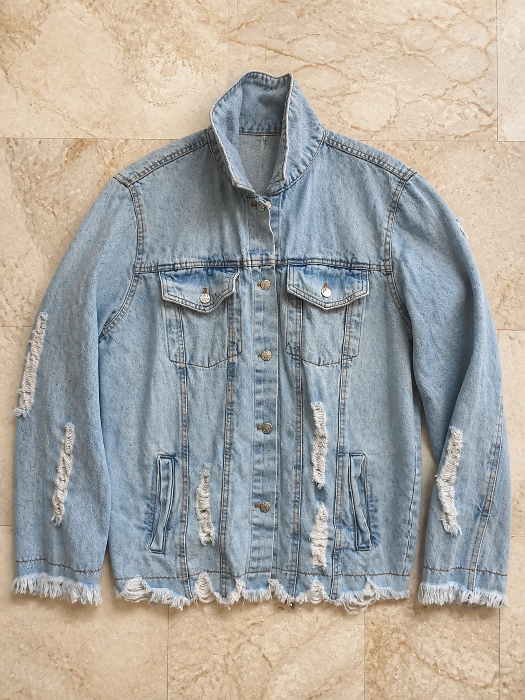 Light blue distressed denim jacket sample on marble