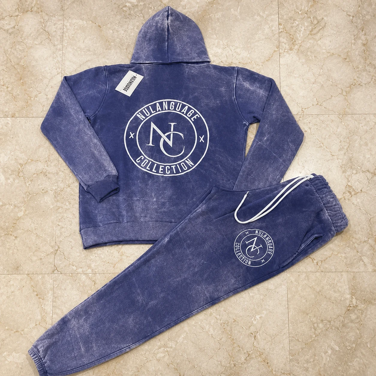 Purple acid-wash hoodie and trouser set arranged on marble